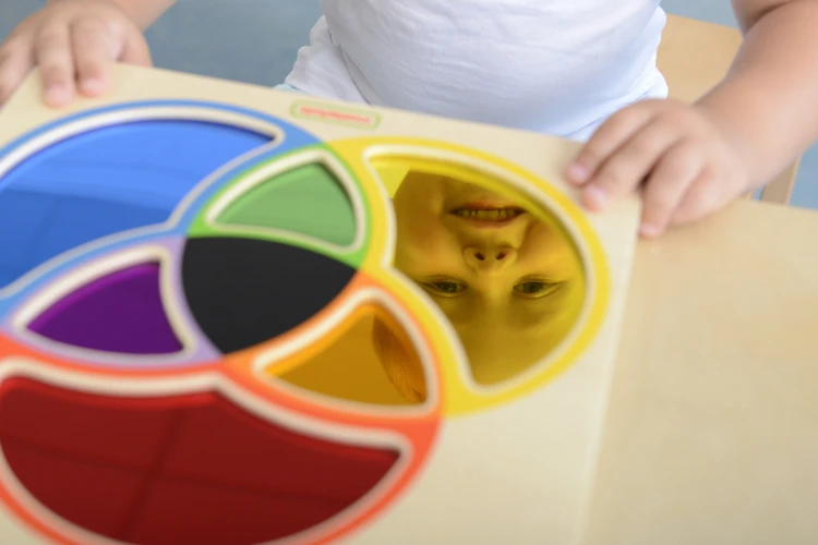 Dziecko używa tablicy edukacyjnej — mieszanie kolorów na lustrze oraz manipulacja elementami
