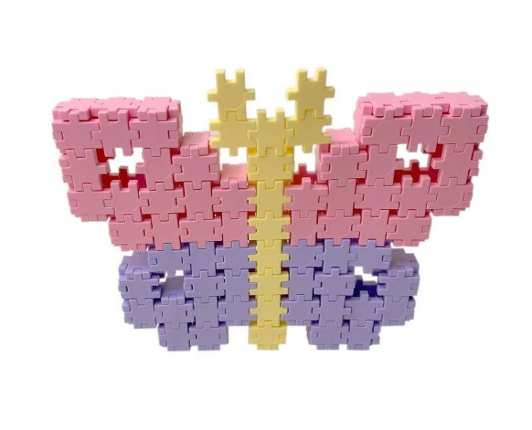 Dziecko tworzy wzór z kafelków Meli Minis Pastel na stole, ćwicząc koncentrację i planowanie przestrzenne.