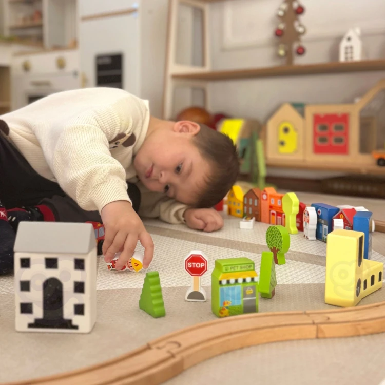 Scenka ułożona z elementów zestawu TOOKY TOY — figurki stoją przy kolorowych budynkach