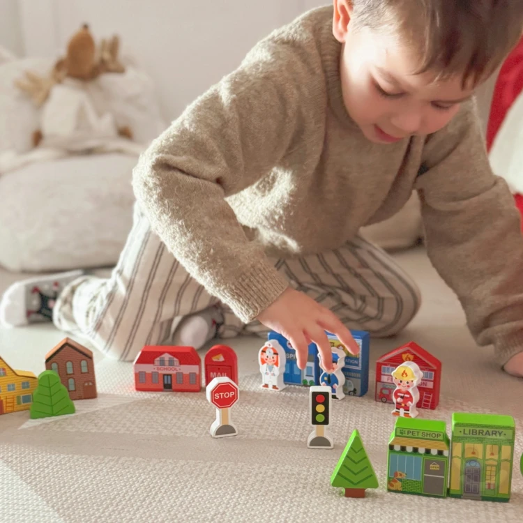 Rozsypane elementy drewnianego zestawu TOOKY TOY na podłodze — różne kształty i barwy
