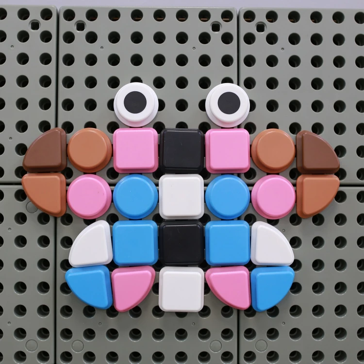 Ujęcie z boku — różne wysokości figur geometrycznych w zestawie kołeczków 64szt pokazane na tle planszy