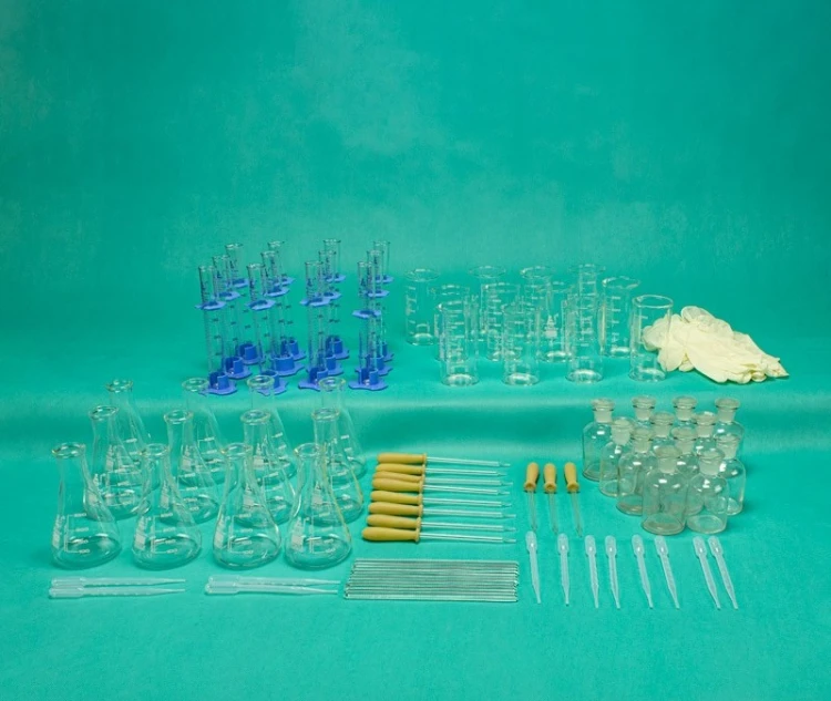 Komplet naczyń do laboratorium ustawionych na stole; widoczne zlewki 250 ml, cylindry 50 ml i kolby 250 ml gotowe do ćwiczeń