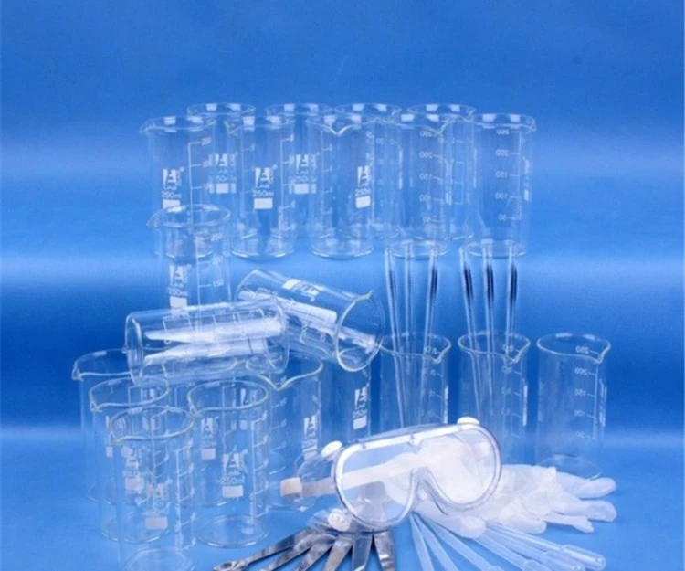 Kompozycja zestawu szkła klasowego z widocznymi zlewkami miarowymi 250 ml, okularami ochronnymi i pipetami, ustawiona na stole laboratoryjnym