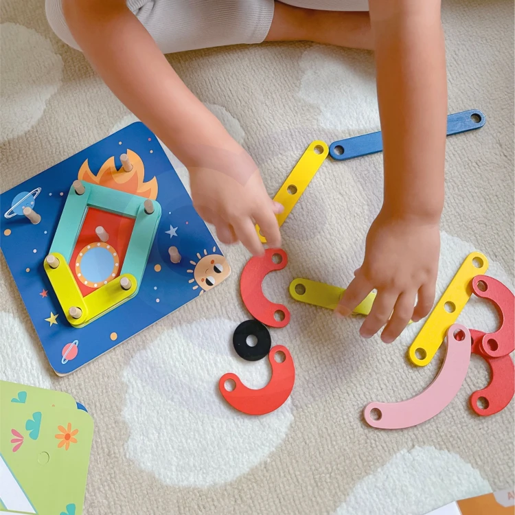 Ręka dziecka układająca kolorowe drewniane klocki na planszy układanki TOOKY TOY